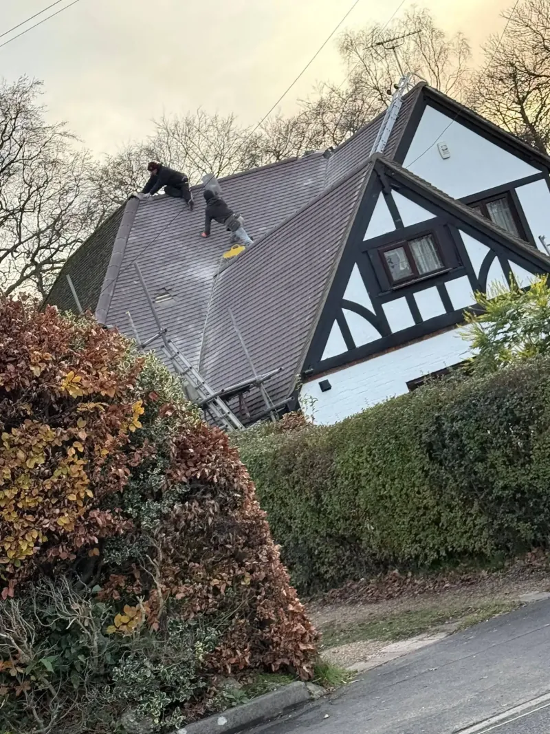 Roofer carrying out tile repairs on a pitched roof in Frimley